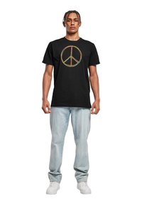 Sort bomulds t-shirt med et flerfarvet fredssymbol grafisk design på fronten, parret med lyseblå denimjeans og hvide sneakers.