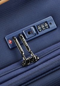 Maleta azul marino con una superficie texturizada, que cuenta con un candado TSA, diales numéricos y dos cremalleras plateadas con la marca "Delsey".