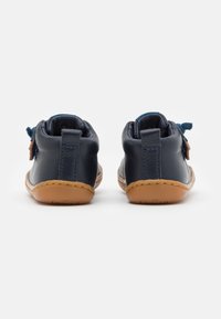 Chaussures en cuir bleu marine avec une semelle en caoutchouc beige, dotées d'un design cousu et d'un accent en tissu à l'arrière.