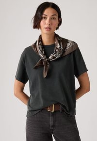 Σκούρο γκρι βαμβακερό μπλουζάκι συνδυασμένο με καφέ φουλάρι με λευκά σχέδια πεϊσλί. Το μοντέλο φορά σκούρο τζιν και καφέ ζώνη.