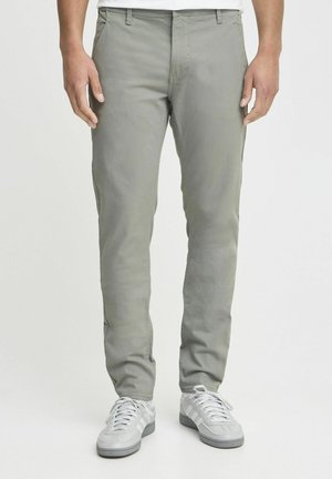 Ljust grå byxor i bomullsblandning med en smal passform, sidofickor och platt front, tillsammans med vita sneakers.