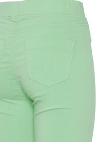 Pantalones vaqueros de mezclilla verde menta con un diseño ajustado, que cuentan con dos bolsillos traseros y una textura suave. Detalles de costura a lo largo de la cintura.