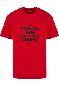 Camiseta de algodón roja con texto negro que dice "VINE COMO UN REY, ME FUI COMO UNA LEYENDA" y un gráfico de una corona encima del texto. Cuello redondo.