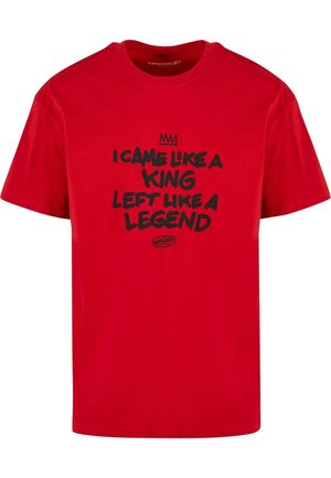 T-shirt en coton rouge avec un texte noir qui dit "JE SUIS VENU COMME UN ROI, JE PARS COMME UNE LÉGENDE" et un graphique de couronne au-dessus du texte. Encolure ronde.