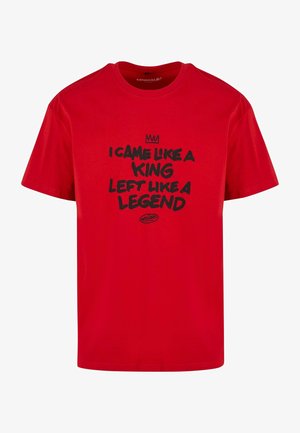 Punane puuvillane T-särk musta tekstiiga, kus on kirjas "Tulid nagu kuningas, lahkusid nagu legend" ja teksti kohal on krooni graafika. Ümar kaelus.