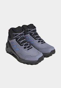 Scarpe da trekking con tomaia in sintetico grigio e nero, pannelli in mesh strutturato, caratterizzate da strisce blu, suole robuste e supporto rinforzato alla caviglia.