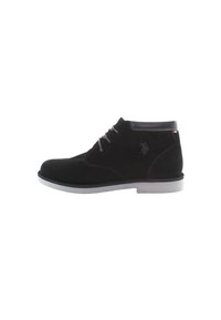Botines de ante negro con cordones grises, una suela blanca y un detalle de cuero en la parte superior. Presentan un logotipo en el costado.
