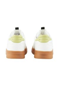 Paire de baskets blanches avec des patchs talons vert clair, des languettes de tirage noires et des semelles épaisses marron, vues de dos sur un fond blanc.