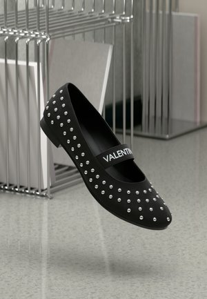Črne ravne čevlje z lesenimi srebrnimi dodatki, gladka površina in oznaka z imenom "VALENTINO". Elegantna in nizkoprofilna zasnova.