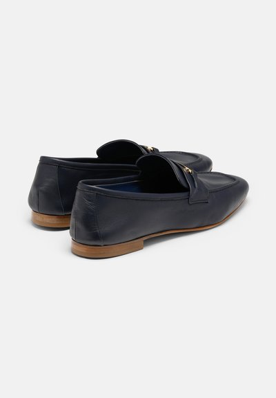 Jūras zila ādas loafers ar zemu profilu, ar zelta toni akcentu un brūnu koka sole. Gluda tekstūra un klasiskā dizaina.