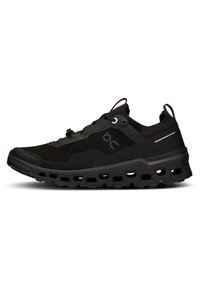 Des chaussures de sport noires dotées d'une tige en maille respirante, d'une surface texturée, d'une semelle épaisse et rembourrée avec des découpes, et d'accents réfléchissants.