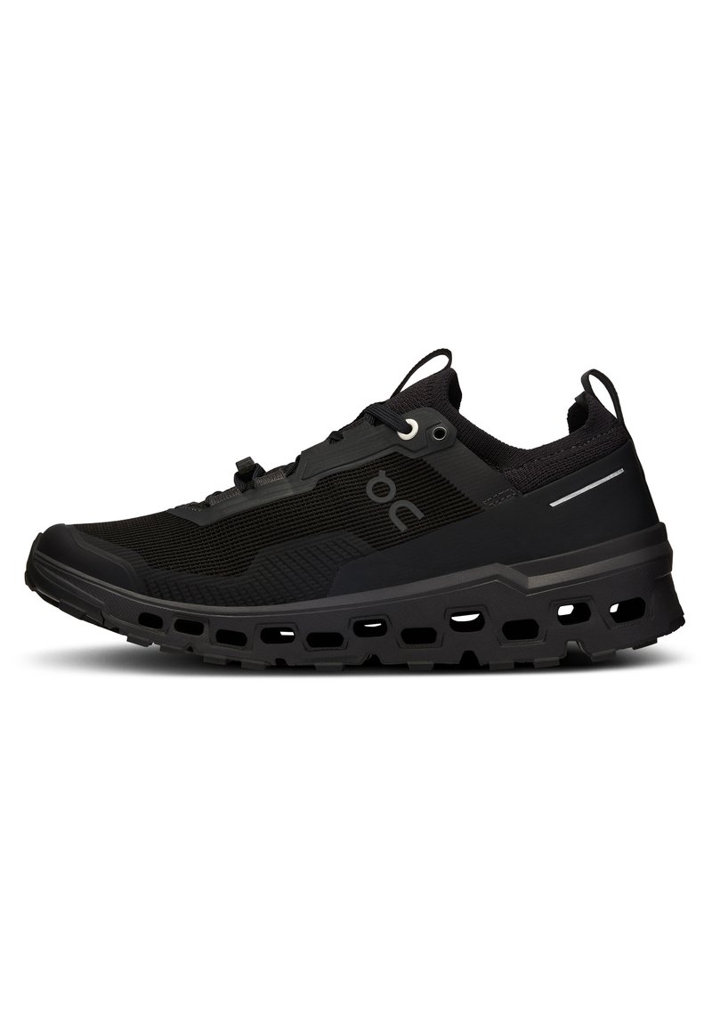 Des chaussures de sport noires dotées d'une tige en maille respirante, d'une surface texturée, d'une semelle épaisse et rembourrée avec des découpes, et d'accents réfléchissants.