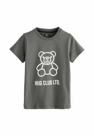 Szürke, rövid ujjú pamut póló, fehér mesebeli medve grafikával, alatta pedig a "HUG CLUB LTD." felirattal.