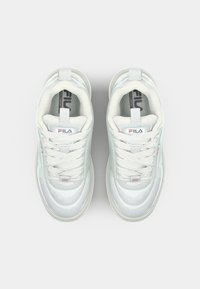White sneakers with a glossy finish, featuring a padded collar, lace-up front, and prominent FILA logo on the side and tongue.