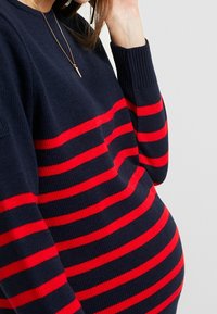 Marineblauer Pullover mit breiten roten Streifen, gestrickte Textur, Rundhalsausschnitt und gerippte Bündchen. Mit einem lockeren Schnitt gestaltet, der Platz für Rundungen bietet.