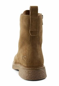 Brauner Wildleder-Stiefelette mit strukturierter Oberfläche, einer Schlaufe an der Rückseite und einer dicken, profilierten Gummisohle. Schlichte Ziernähte.