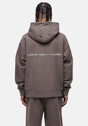 Oversized, hooded sweatshirt in muted brown with a textured finish. Features white cursive text across the back and ribbed cuffs.