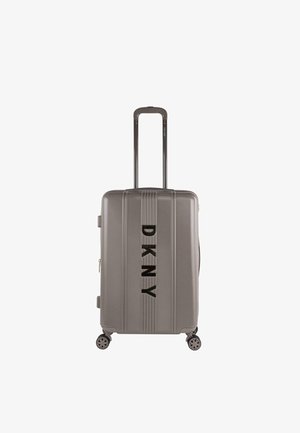 Maleta dura gris con ruedas dobles, estrías verticales y un logotipo negro prominente en la parte frontal. Incluye asa retráctil.