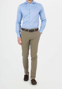 Camicia azzurro chiaro a maniche lunghe, fitted, stile con bottoni; abbinata a pantaloni beige slim-fit e scarpe marroni scure. Design semplice, senza fantasie.