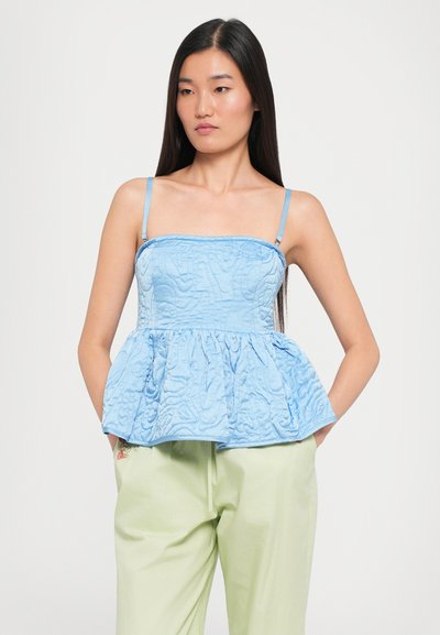 Top peplum de culoare albastru deschis, cu bretele ajustabile din saten, material texturat și un model matlasat. Asortat cu pantaloni de culoare verde deschis.
