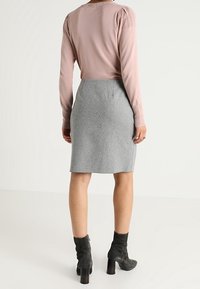 Ljusrosa stickad tröja med puffärmar kombinerat med en grå knälång blyertskjol. Svarta ankelstövlar med tjock klack fulländar looken.