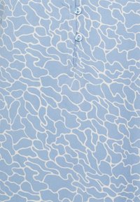 Světle modrá tkanina s bílým abstraktním vzorem, s légou s knoflíky. Hladká textura se měkkým a splývavým vzhledem.