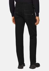 Černé džíny se rovný fit, s dvěma zadními kapsami a jemným prošíváním. V kombinaci s černými sportovními botami.