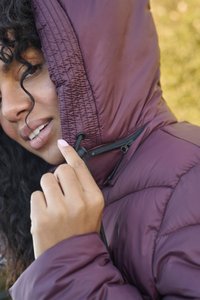 Bordeaux hættepufferjakke med synlig syning og lynlåsdetalje, der har en justerbar snor ved halsen og en glat, skinnende tekstur.