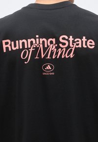 Μαύρη πίσω πλευρά μπλουζάκι με ροζ κείμενο "Running State of Mind" και λογότυπο Adidas με "Since 1949" κάτω από το κείμενο.