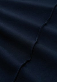 Navyblauem Stoff mit glatter Textur, der subtile Wellen und eine sichtbare Naht in der Mitte aufweist.