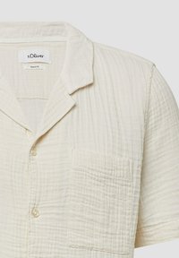 Lichtbeige kortekorte mouwen shirt gemaakt van textuurstof. Voorzien van een geplooide kraag, knoopsluiting en een borstzak.