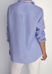 Ljust lila skjorta med knappar och rullade ärmar, som har en ryggsömnadsdetalj och rundad nederkant, tillverkad i ett mjukt, texturerat tyg.