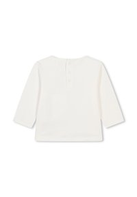 Haut blanc à manches longues en coton avec un col rond, doté de trois boutons dans le dos. Texture lisse, design minimaliste.