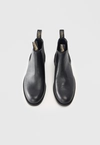Czarne skórzane botki za kostkę z elastycznymi panelami bocznymi i pętelkami do zakładania. Gładka faktura i zaokrąglony nosek z płaską podeszwą.