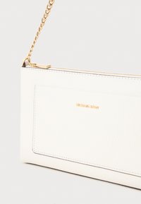White leather clutch with a zip closure, gold chain strap, and embossed logo. Features a smooth texture and minimalistic design.