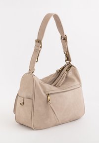 Beige faux læder håndtaske med en struktureret form, justerbar skulderrem, guld hardware detaljer og en frontlomme med lynlås og en kvast.