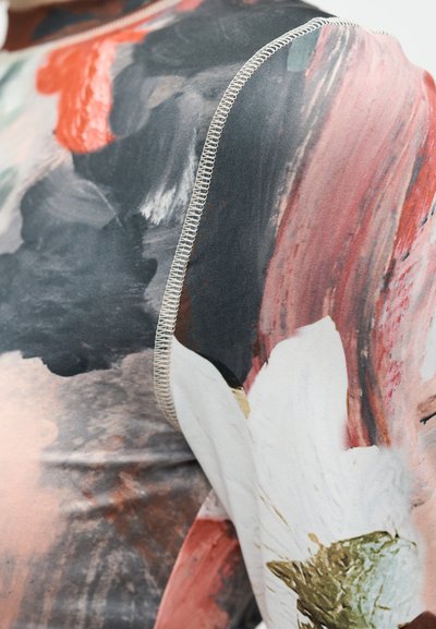 Nærbilde av et stoff med et blomsterdekorert mønster i svarte, rosa og hvite strøk, kantet med en kontrasterende sydd sømdetalj.