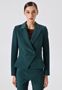 Blazer doppiopetto teal in tessuto strutturato con vita a peplo, colletto stondato e pantaloni coordinati, caratterizzati da linee pulite e bottoni.