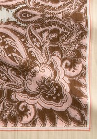 Bruin en roze gestoffeerd materiaal met ingewikkelde paisley- en bloemmotieven, met een zachte textuur en afgewerkte randen.