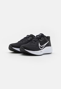 Zwarte sportieve schoenen met een ademende mesh bovenkant, wit logo, gestructureerde zool en een gevoerde kraag voor comfort en ondersteuning.