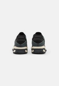 Czarno-szare sneakersy mają teksturowaną cholewkę, wyściełaną podeszwę oraz wyraźne akcenty na pięcie z otworami wentylacyjnymi dla lepszej oddychalności.