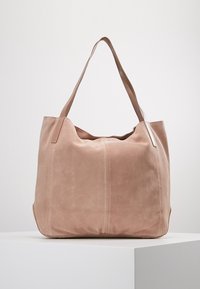 Sac fourre-tout en daim rose doux avec deux longues bandoulières, comprenant un compartiment principal et des détails de couture discrets sur le devant.
