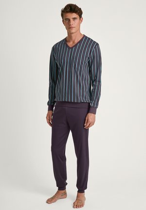 Ensemble de vêtements de détente rayés comprenant un haut à col en V avec de fines rayures verticales multicolores et un pantalon fuselé violet uni. Tissu doux, coupe décontractée.