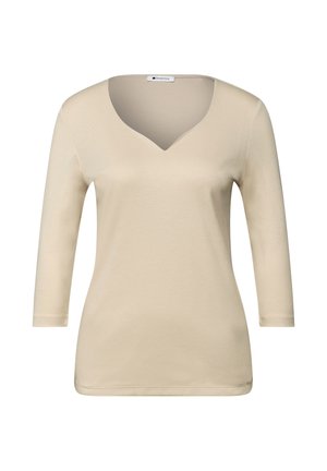 Béžové tričko s dlouhým rukávem a výstřihem do V, vyrobené z měkké látky. Má přiléhavý střih a hladkou texturu, bez viditelných vzorů nebo ozdob.