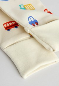 Krémová tkanina s farebnými vzormi vozidiel, vrátane červených autobusov a modrých áut. Obsahuje rebrované manžety pre pohodlné priliehanie.
