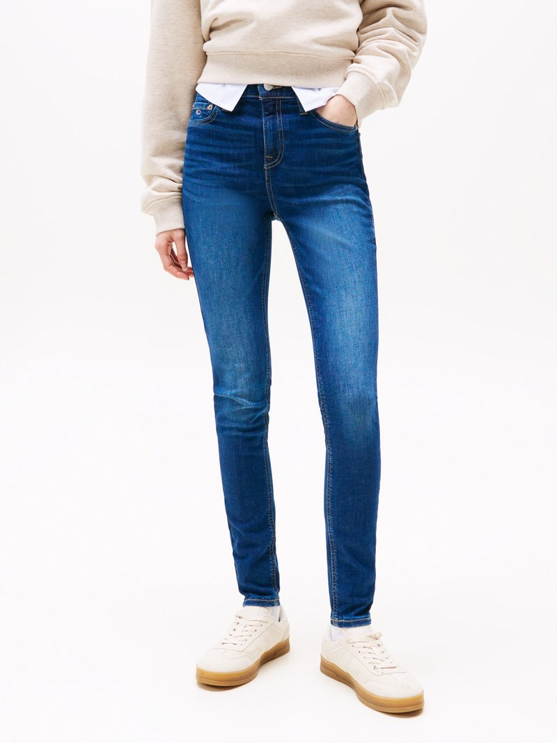 Slanke blå jeans laget av denim, med høy midje, subtil fading og sømdetaljer, kombinert med hvite joggesko.