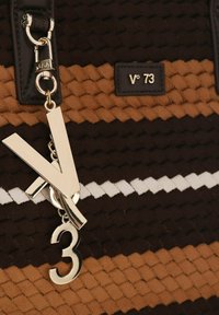 Geweven tas in bruin en beige met een gouden hardware charm met de letter "V" en het cijfer "3", en een witte accentstreep.