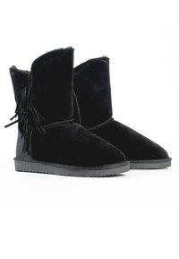 Botas de tobillo de ante negro con un interior suave, que presentan un diseño deslizante y detalles de flecos en el lado exterior. Suela de goma para tracción.