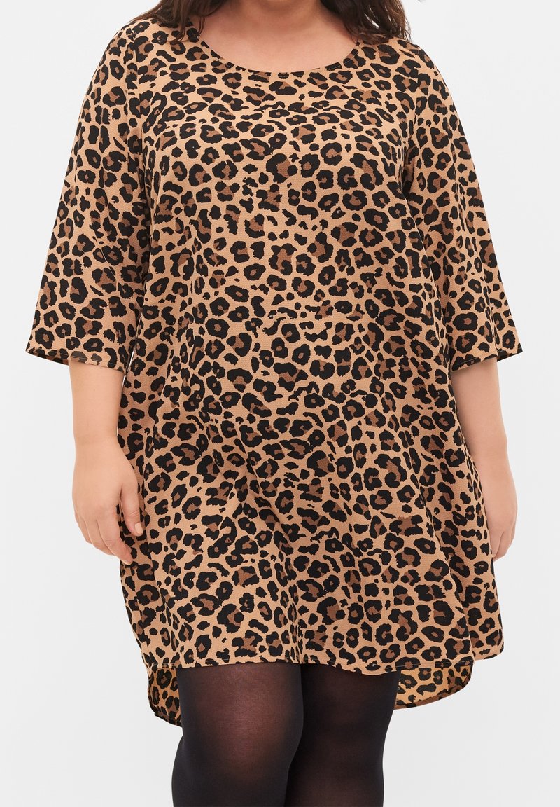 Robe tunique à imprimé léopard, manches courtes, coupe décontractée, fond brun clair, taches noires, tissu doux, décolleté arrondi, longueur mi-cuisse.