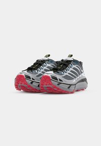 Des chaussures de course avec une tige grise et noire, des accents réfléchissants et des semelles extérieures rose vif. Comprend des matériaux texturés et un système de lacets sécurisé.